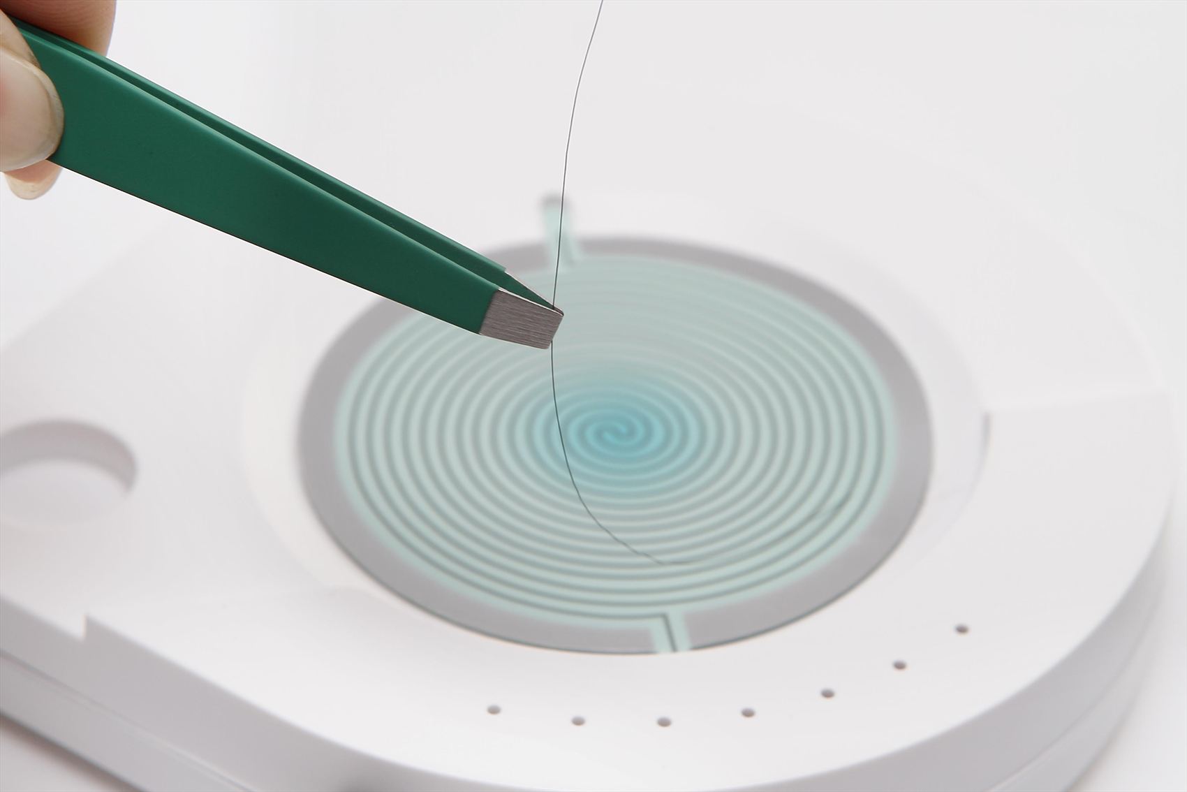 Colocación de una hebra de cabello con pinzas en el sensor del dispositivo S-DRIVE